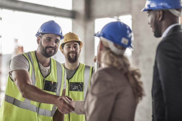 Construction worker and executive shaking hands in construction site